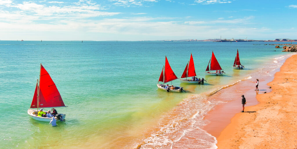 Colorful camp boats lined up on a sunny beach at Camp Fairbridge, capturing the essence of fun and adventure