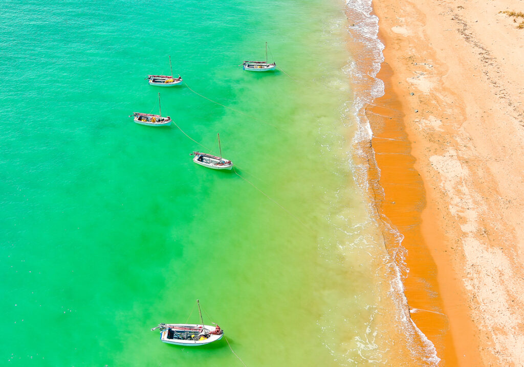 Vibrant boats anchored on the beach at Dampier Camp Fairbridge, awaiting participants' adventure