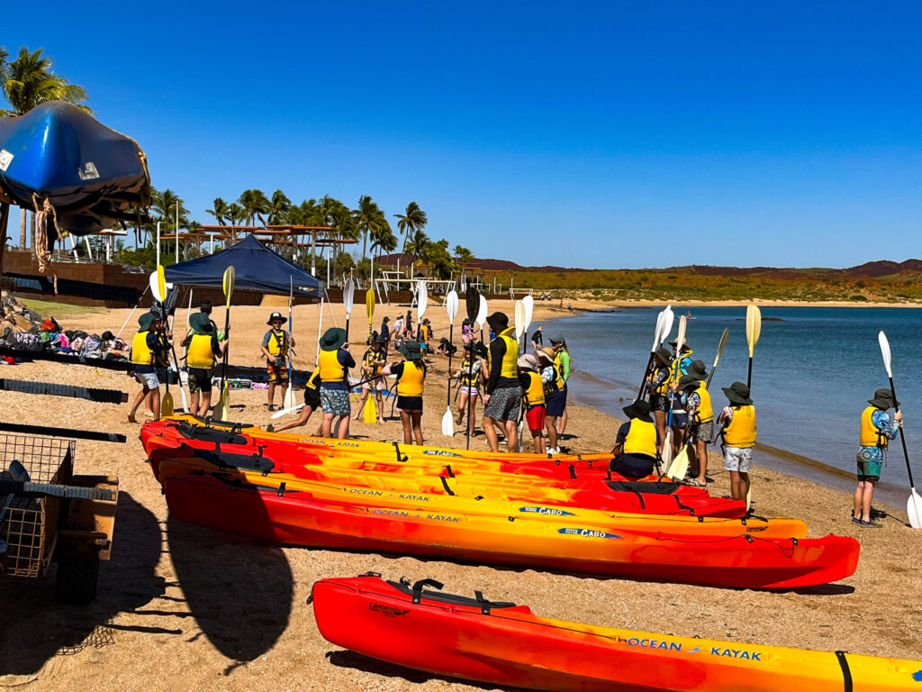 Group of people in life vests holding paddles, waiting for instructions for a kayaking activity at Camp Fairbridge
