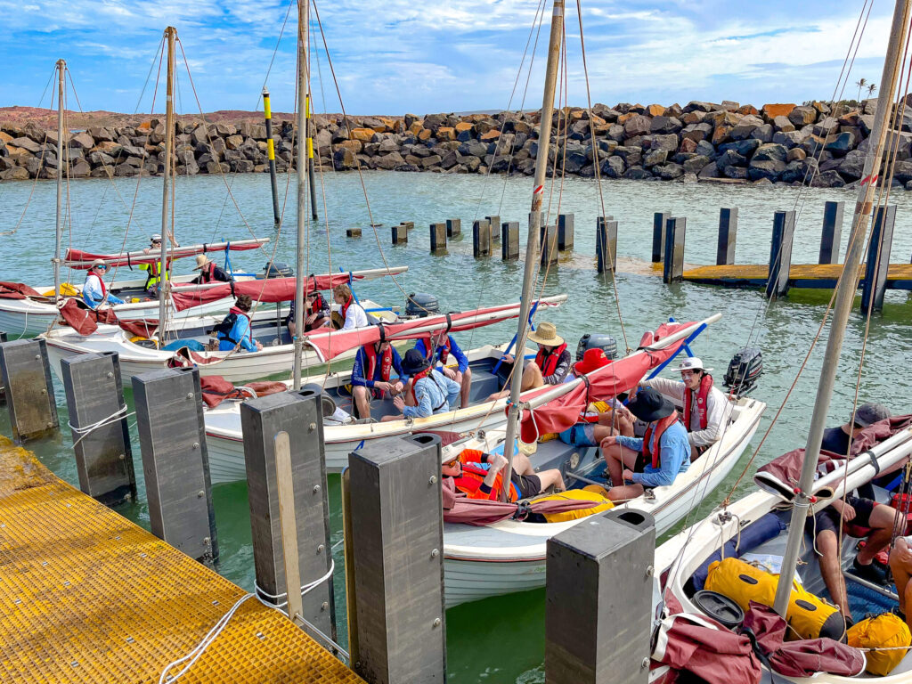 Group of individuals sitting on a boat, getting ready to sail at Camp Fairbridge beach