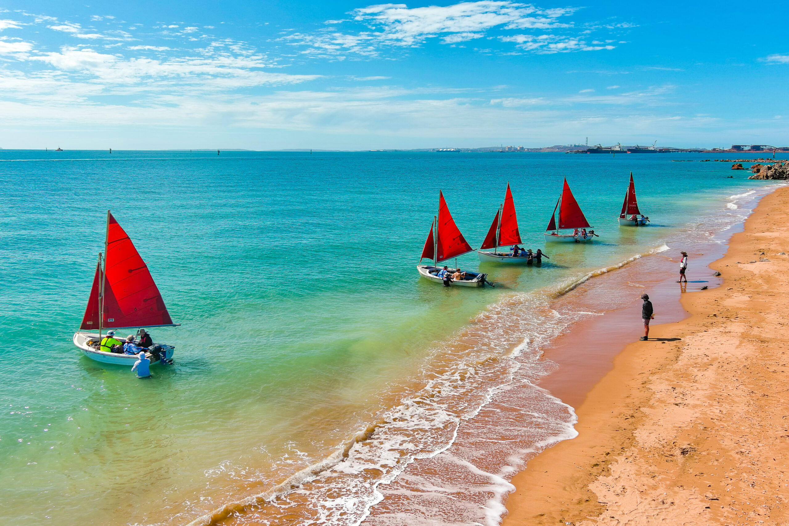 Colorful sailboats lined up on a sunny beach at Camp Fairbridge, capturing the essence of fun and adventure
