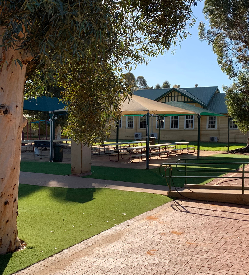 A vibrant park with tables and chairs at Geraldton Camp Fairbridge, perfect for relaxation and gatherings