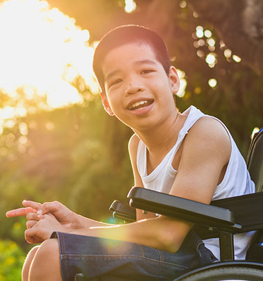 A kid sitting down enjoys watching the fun activities and beautiful scenery at Camp Fairbridge