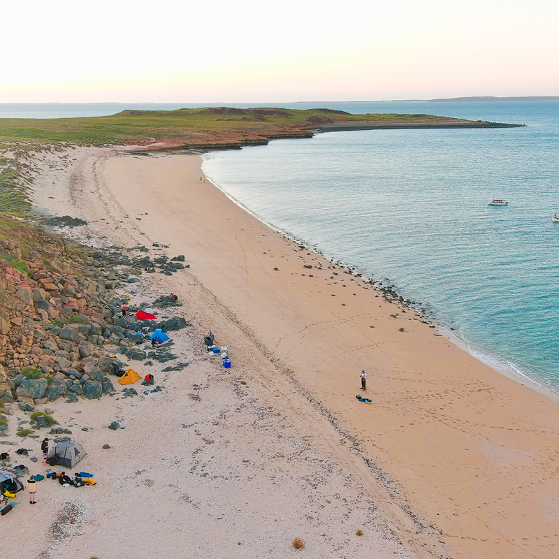 Stunning aerial view of Camp Fairbridge beach, with people camping on the shore during a sea trekking activity