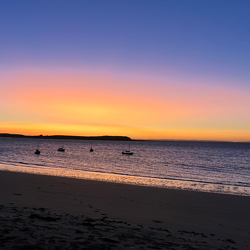 Captured a stunning sunset at Camp Fairbridge beach, with boats gently floating in the water during a Sea Trekking activity