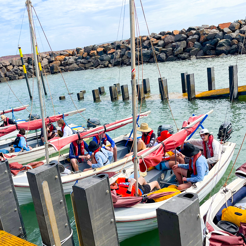 Group of individuals sitting on a boat, getting ready to sail at Camp Fairbridge beach