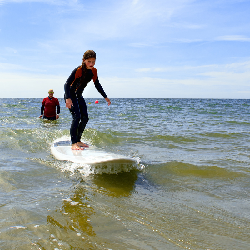 An instructor teaching a student during a surfing activity at Camp Fairbridge Beach