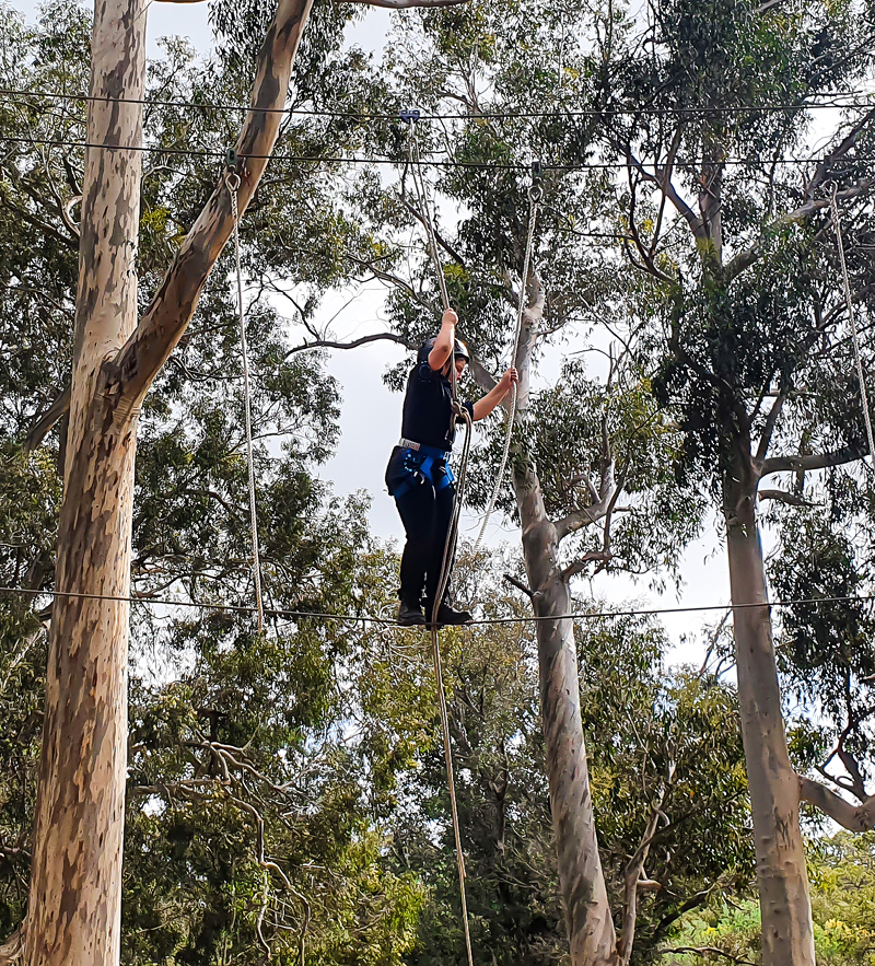 A person in a helmet and harness enjoys an outdoor ropes course at Camp Fairbridge in Pinjarra