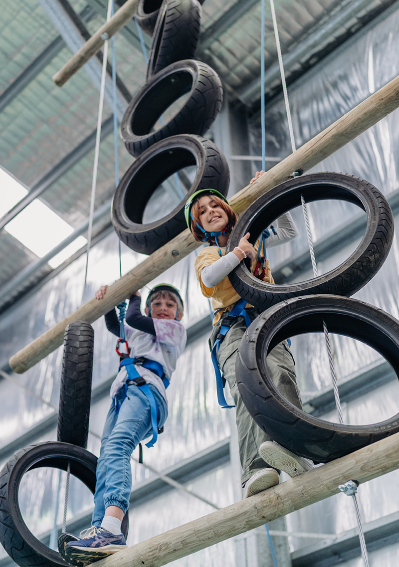 Two children enjoy a ropes course in the indoor play area at Camp Fairbridge