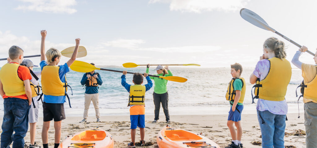 An instructor demonstrating the correct way to hold a paddle for kayaking to children at Dampier Peninsula camping site