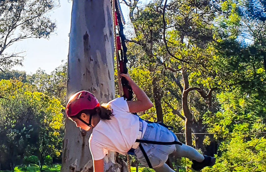 A young woman wearing a harness and helmet during high ropes course outdoor activity at Camp Fairbridge A young woman wearing a harness and helmet during high ropes course outdoor activity at Camp Fairbridge
